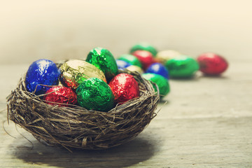 retro chocolate easter eggs in a nest on a rustic wooden table,