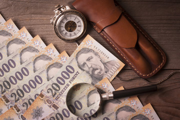 Money , retro clock, magnifying glass and pen case on a wooden table - Time is money concept