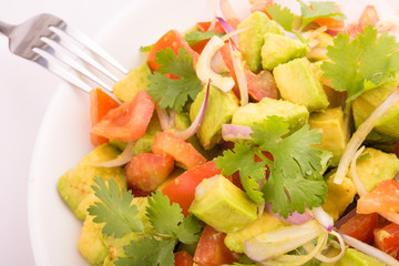 Fresh avocado Salad  with tomatoes, purple onion on the white dish. Healthyt food concept
