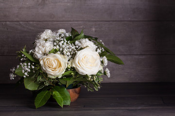 Wedding bouquet of white roses on a wooden table.