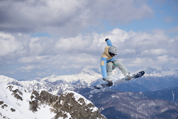 Flying snowboarder on mountains. Extreme sport.