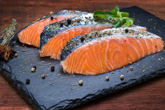 Fresh salmon portions on black tile.