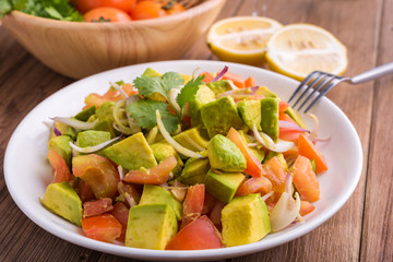 Fresh avocado Salad  with tomatoes, purple onion on the white dish. Healthyt food concept