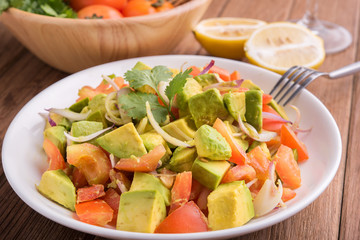 Fresh avocado Salad  with tomatoes, purple onion on the white dish. Healthyt food concept