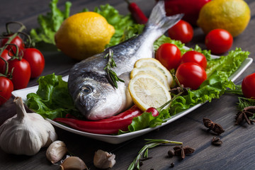 Fresh dorado fish on wooden cutting board with vegetable