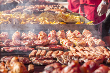 Different kind on grilled meat and sausages with smoke and steam from the grill