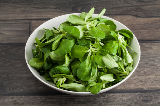 Salad Leaves In Bowl On Wooden Planks Background