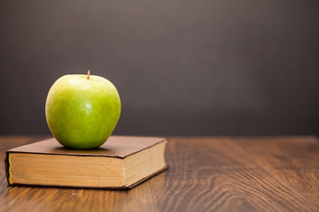 Naklejka premium apple and book on wooden table
