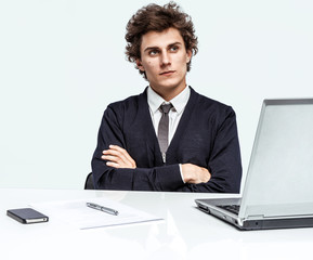 Serious businessman with arms across at the workplace in the office and thinking on grey background. Depression and crisis concept