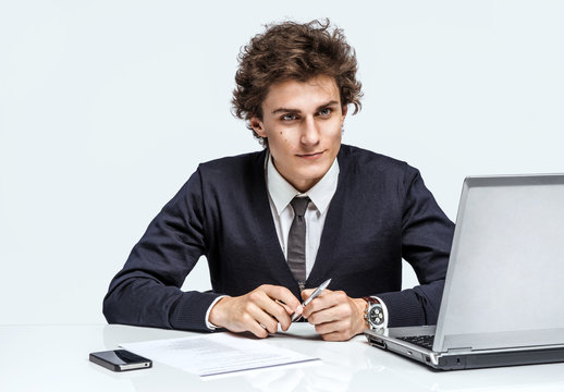 Ambitious young businessman with serious look face / businessman at the workplace working with computer on grey background. Depression and crisis concept