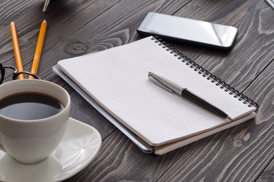 open notepad with blank pages, pen and cup of coffee