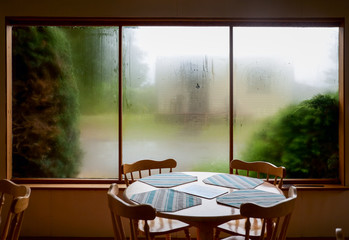 Empty table and chairs against misted window at casual bistro