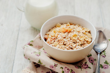 
healthy breakfast of muesli and oatmeal with fruit , milk and dried fruit on wooden background