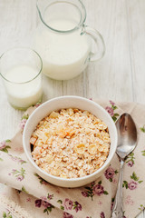 
healthy breakfast of muesli and oatmeal with fruit , milk and dried fruit on wooden background