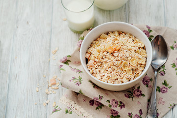 
healthy breakfast of muesli and oatmeal with fruit , milk and dried fruit on wooden background