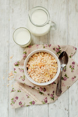 
healthy breakfast of muesli and oatmeal with fruit , milk and dried fruit on wooden background