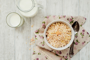 
healthy breakfast of muesli and oatmeal with fruit , milk and dried fruit on wooden background