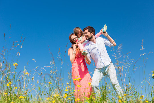 Family On Meadow In Front Of Blue Sky