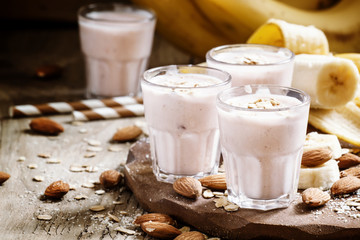Banana smoothie with milk, oatmeal and almonds on the old wooden