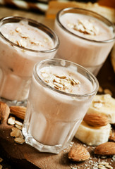 Banana smoothie with milk, oatmeal and almonds on the old wooden