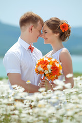 Happy bride and groom in a camomile field 