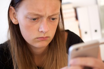 Teenager guckt kritisch auf ihr Smartphone