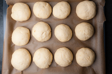 rohe selbstgemachte Teiglinge für Brioche/Hamburgerbrötchen auf einem Backblech mit Backpapier