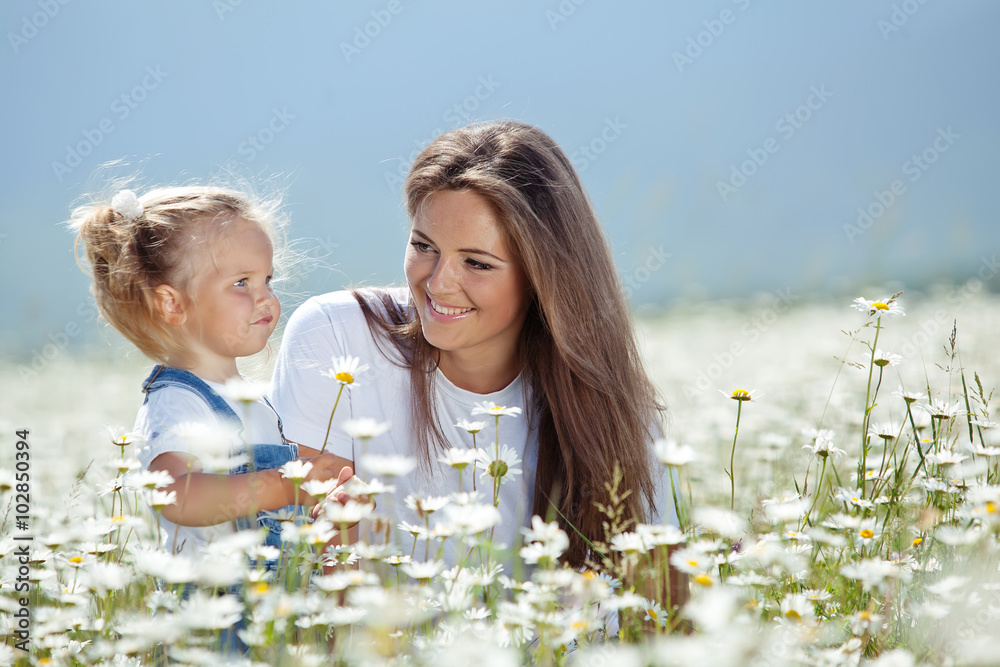 Wall mural mother with daughter on nature in a camomile field