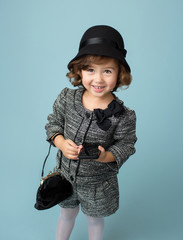 Child Fashion: Girl in a cute outfit in a fedora hat and with a purse and cell phone modeling clothing