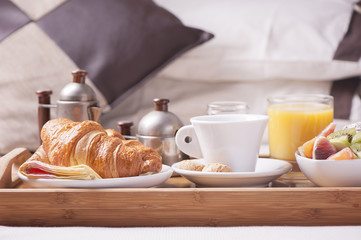 Tray with breakfast on a bed in a hotel room