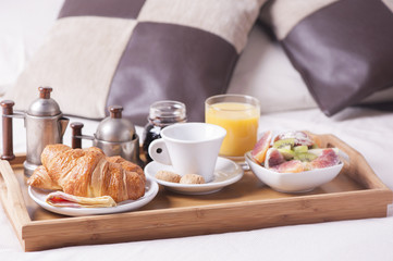 Tray with breakfast on a bed in a hotel room