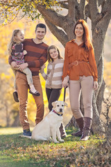 Happy family on nature with a labrador