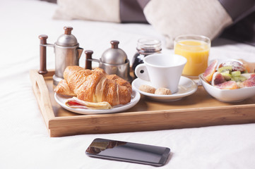 Tray with breakfast on a bed in a hotel room