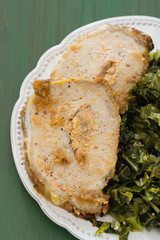 pork with cabbage on white plate on green wooden background