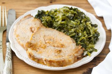 pork with cabbage on white plate on brown wooden background