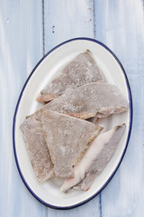 frozen fish in white dish in blue wooden background
