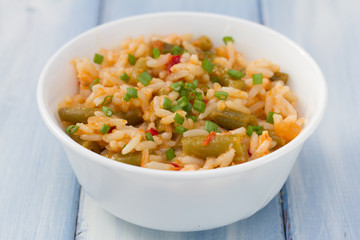 rice with vegetables in white bowl on blue wooden background