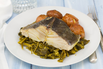 cod fish with potato and vegetables on white plate and glass of water