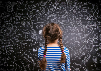 Girl  against big blackboard with formulas, back view