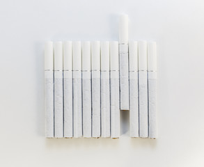 Cigarette with a white filter laid out in a row on a white backg