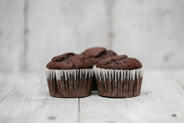 Three chocolate muffins on wooden surface