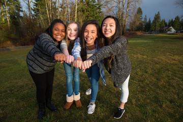 Group of four kids making a unified fist to demonstrate girl pow
