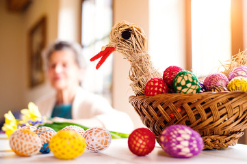 Basket with Easter eggs and hen in senior woman house