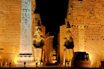  Egypte. Verlichte Luxor-tempel. De rode granieten obelisk en twee zittende beelden van Ramses II voor de eerste pyloon © WitR