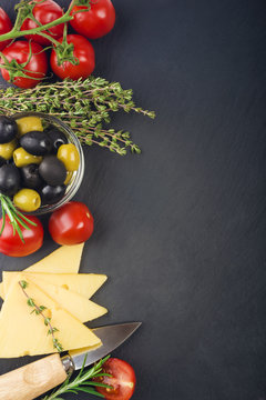 cheese with fresh herbs, black and green olives, cherry tomatoes, selective focus