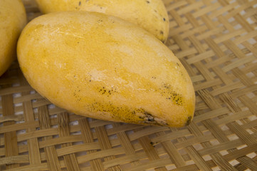 three mangoes on bamboo tray