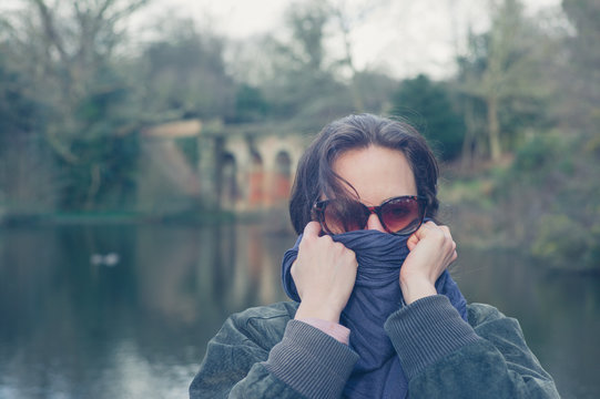 Woman wrapping up her face by lake in park