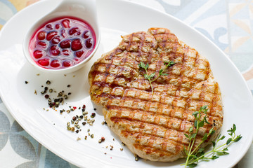 Delicious fried steak with sauce and spices on a white plate