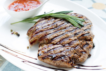 Delicious fried steak with sauce and spices on a white plate