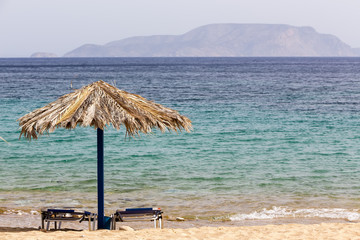 Blue sea, golden sand, sunbeds and umbrellas on the beach. Ios i